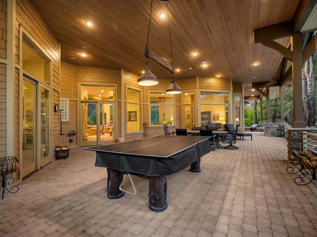 6 of 52. Massive covered patio designed for year-round entertaining with lounge seating, recreation space, wood ceilings, and beautiful views of the surrounding forest landscape.