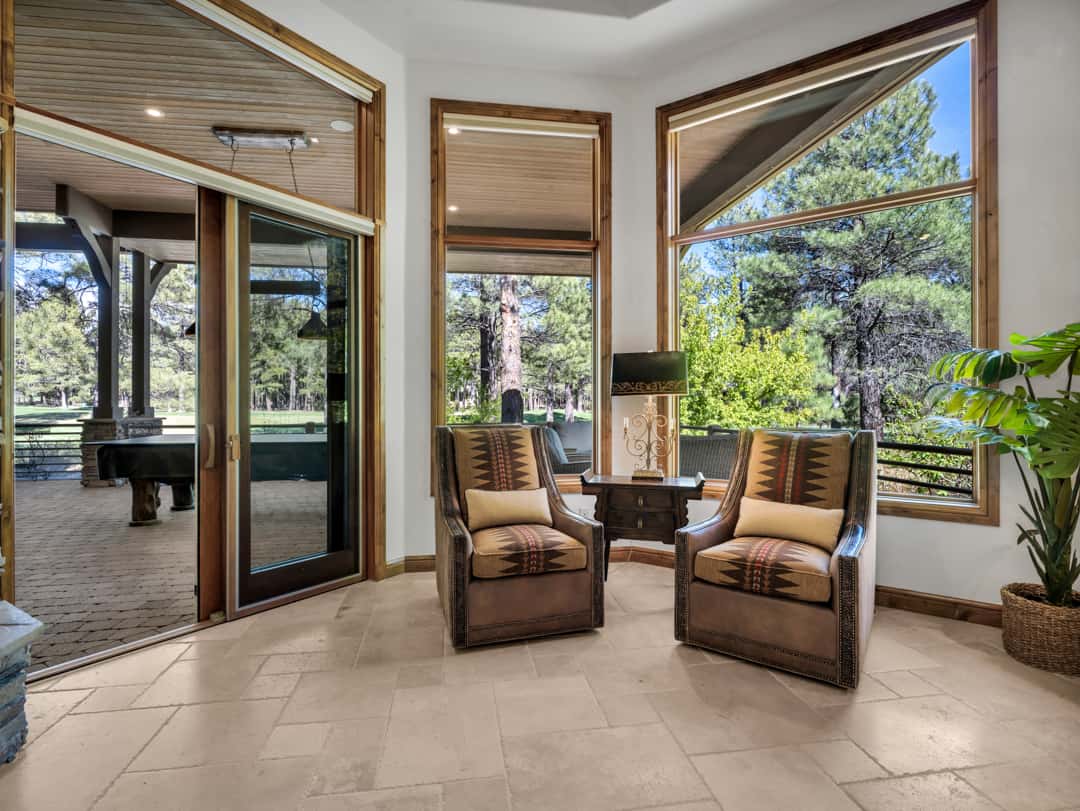 18 of 52. Relaxing bedroom sitting area with panoramic windows, natural light, and tranquil pine tree views that bring the beauty of Flagstaff indoors.