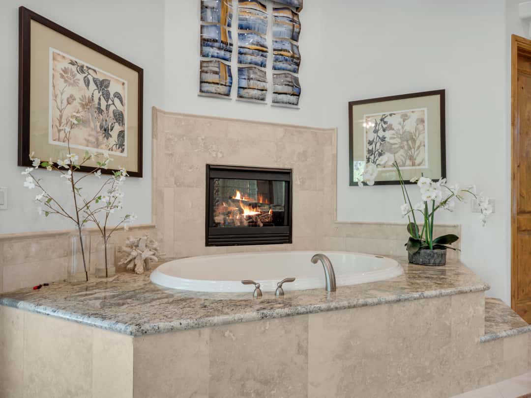 21 of 52. Luxury primary bathroom featuring a relaxing soaking tub, elegant fireplace detail, granite countertops, and spa-inspired finishes perfect for mountain retreat living.
