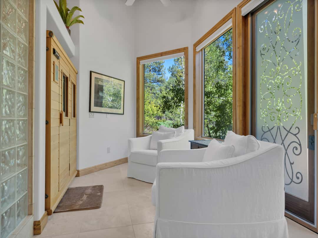 22 of 52. Private wellness area with infrared sauna, peaceful seating space, and large windows bringing natural light and forest views into the luxurious primary suite.