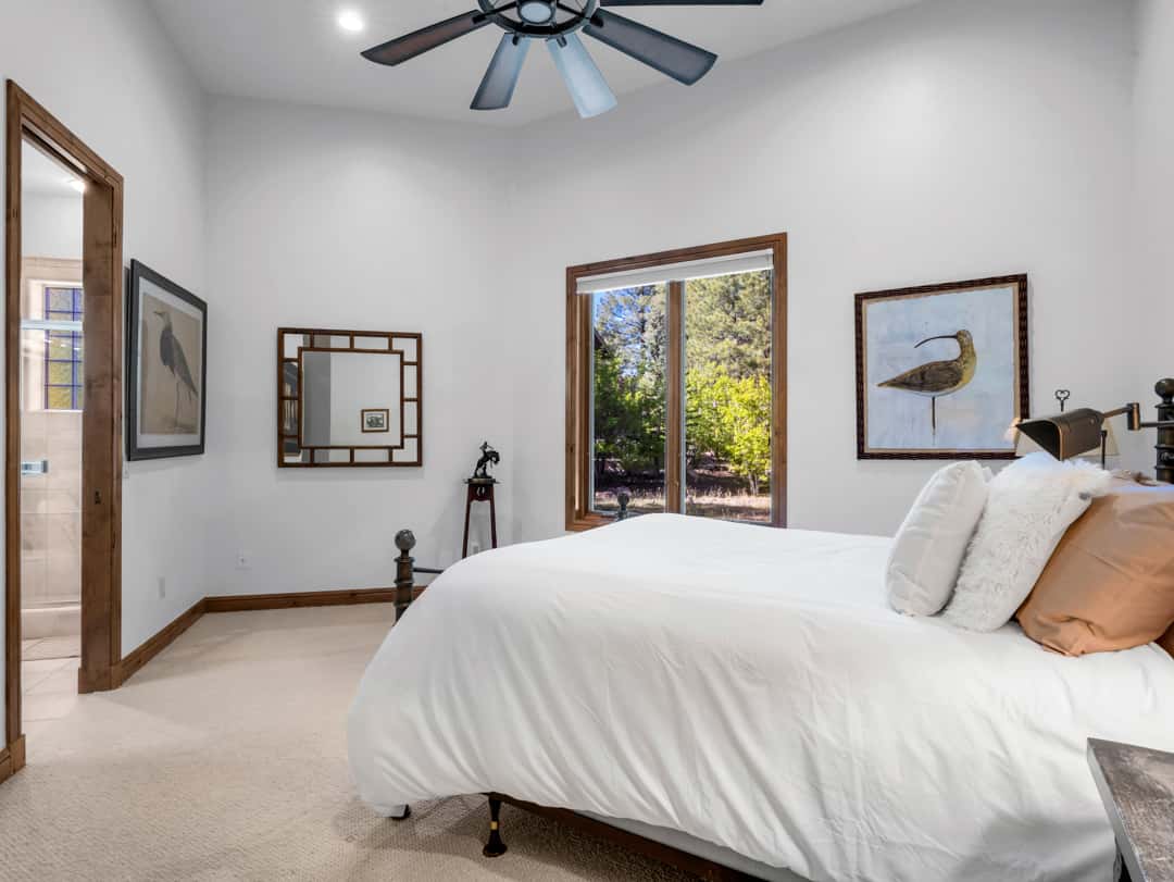 24 of 52. Inviting guest bedroom with large picture windows, soft natural light, high ceilings, and peaceful mountain-inspired design throughout the luxury home.