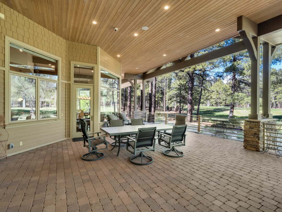 35 of 52. Beautiful outdoor entertaining space with expansive patio seating, covered gathering areas, and peaceful forest surroundings in luxury Flagstaff living.