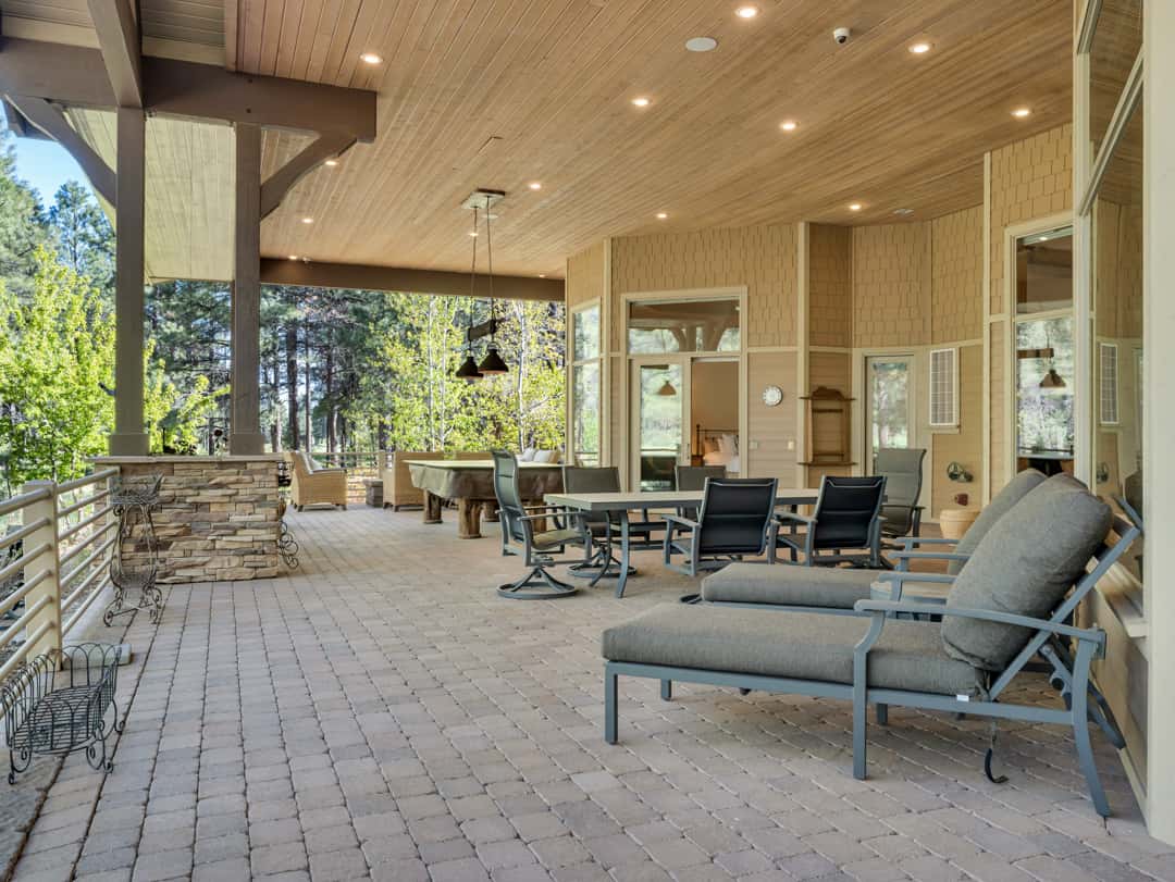 41 of 52. Spacious covered outdoor living area designed for entertaining with golf course views, multiple seating spaces, and beautiful natural surroundings.