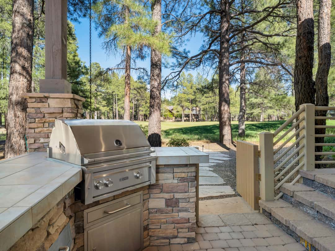 42 of 52. Built-in BBQ station with stone accents and scenic golf course surroundings, ideal for outdoor cooking and entertaining in Flagstaff.