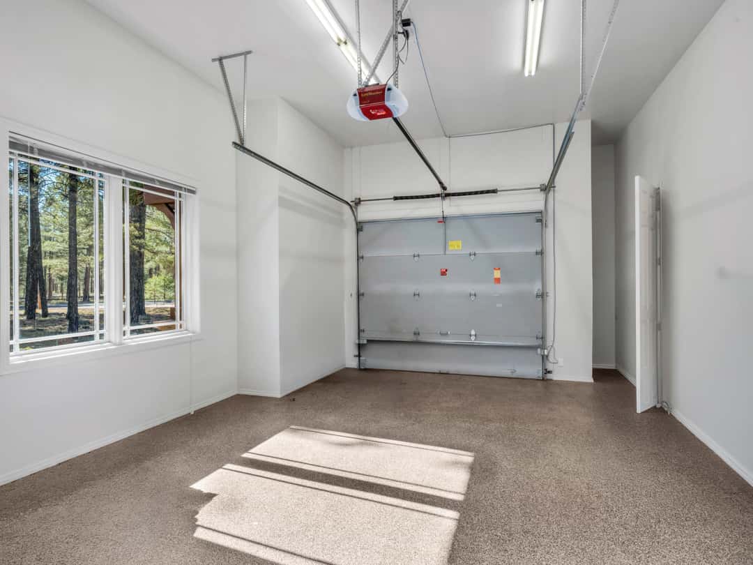 43 of 52. Large garage with epoxy flooring, bright lighting, and high ceilings offering excellent storage and parking flexibility for multiple vehicles.