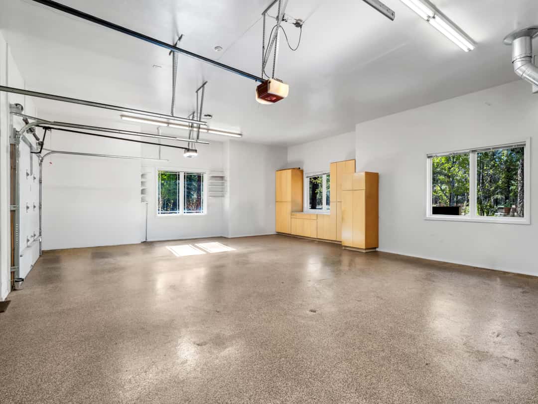 46 of 52. Oversized garage with custom cabinetry, generous storage options, bright windows, and ample room for hobbies, tools, and vehicles.