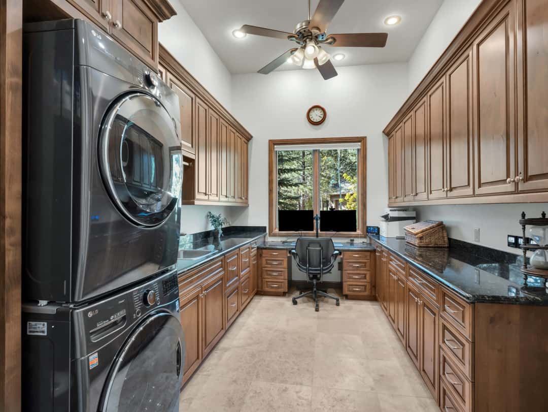 47 of 52. Spacious laundry room with extensive cabinetry, built-in workspace, granite counters, and exceptional storage solutions for everyday convenience.