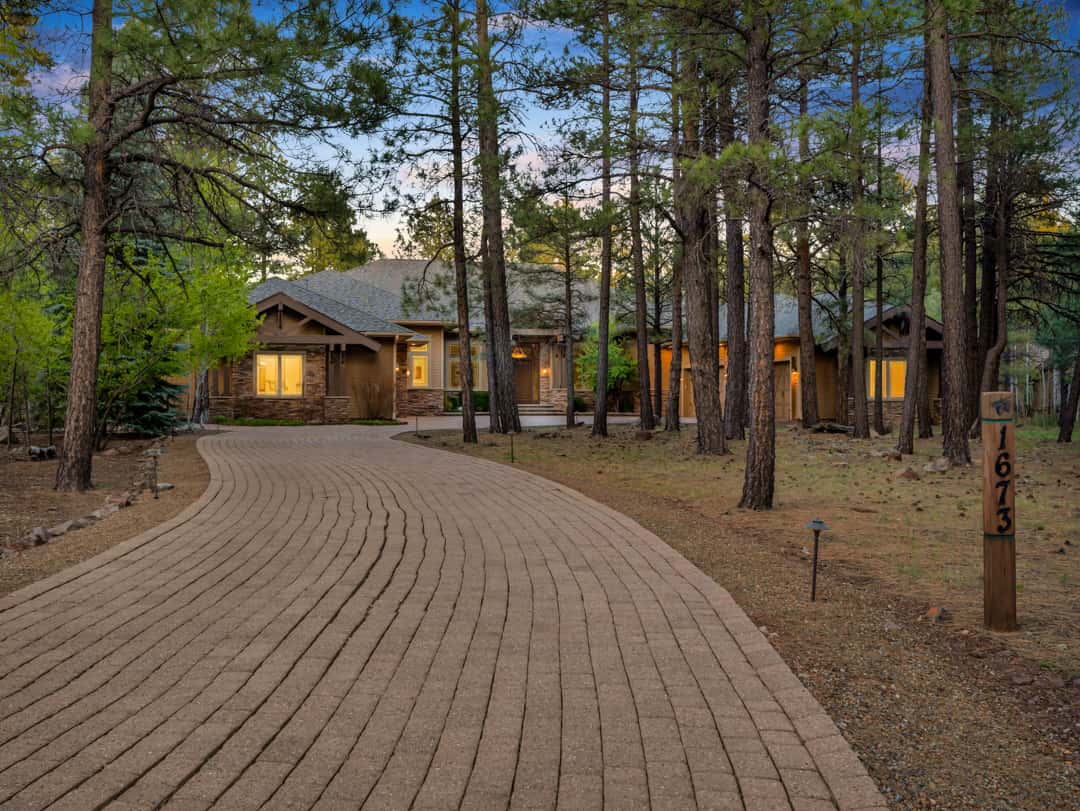 51 of 52. Gorgeous custom home surrounded by mature pine trees featuring a grand driveway, elegant architecture, and impressive outdoor presence in Flagstaff.