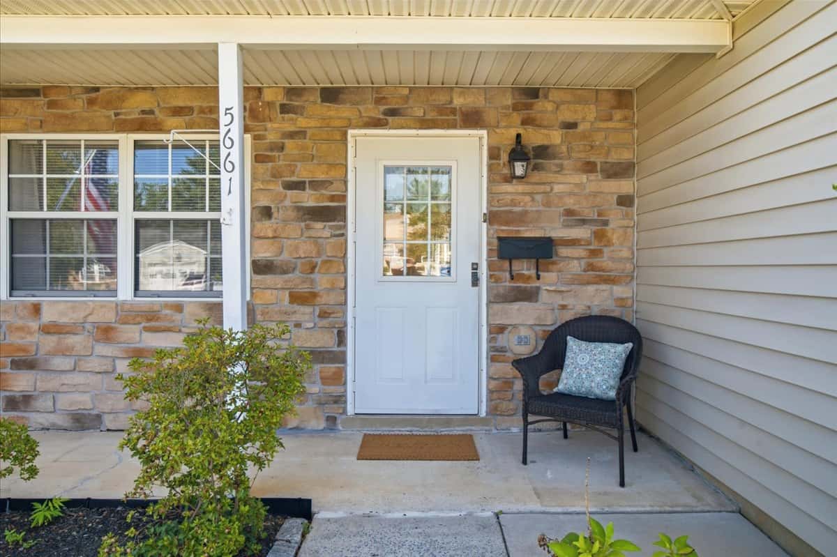 2 of 39. Welcoming entryway features a cozy chair and tasteful landscaping, perfect for enjoying outdoor moments.