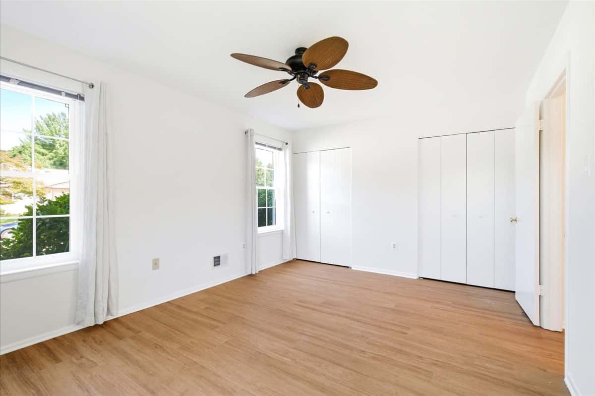 19 of 39. Bright and spacious bedroom featuring large windows, ample storage, and a modern ceiling fan.