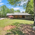 This inviting home features a spacious yard, surrounded by lush greenery and natural light throughout.