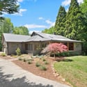 Welcoming home surrounded by lush greenery, featuring a spacious layout and beautiful landscaping for outdoor enjoyment.