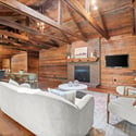 Spacious open-concept living area with exposed beams, fireplace, and a seamless flow into the kitchen.