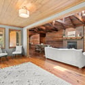 Spacious living area features exposed wood beams, natural lighting, and a cozy fireplace for relaxation.