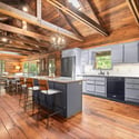 Experience a warm, open kitchen and dining area with natural light and rustic wooden beams throughout.