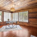 Bright workspace featuring wood-paneled walls, ample natural light, and cozy views from large windows.