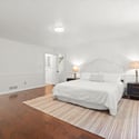 Spacious bedroom featuring hardwood floors, ample natural light, and convenient access to an adjacent bathroom.