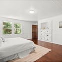 Bright and spacious bedroom featuring large windows, hardwood floors, and ample storage for comfort and convenience.