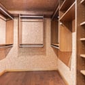 Spacious walk-in closet featuring rich wood finishes and ample shelving for organized storage solutions.