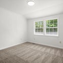 Bright, spacious room with freshly painted walls and natural light streaming in from dual windows.