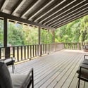 Spacious deck surrounded by lush greenery, perfect for outdoor gatherings and relaxation in nature.
