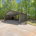 This spacious carport offers convenient coverage and easy access in a tranquil wooded setting.