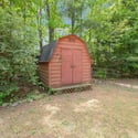 A unique backyard shed nestled among lush greenery, perfect for storage or creative projects.