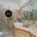 Bright bathroom featuring colorful tiled walls, modern fixtures, and ample natural light for a refreshing ambiance.