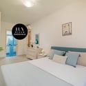 Bright and airy bedroom with modern furnishings, featuring a balcony and convenient storage options.