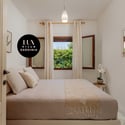 Cozy bedroom featuring natural light, modern decor, and tranquil views of surrounding greenery.