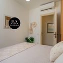 Cozy bedroom with modern amenities, featuring natural light and a calming atmosphere for restful nights.