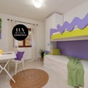 Bright and playful bedroom featuring a loft bed, work desk, and vibrant decor for a youthful vibe.