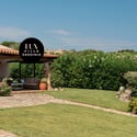Discover this inviting villa in Sardinia, featuring lush gardens and a welcoming outdoor patio space.