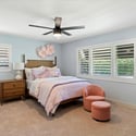 Light-filled guest bedroom with plantation shutters, ceiling fan, and comfortable proportions for overnight guests or everyday use.