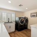 Functional laundry room with quartz countertops, utility sink, storage cabinetry, and efficient workspace design.