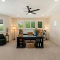 Bright and versatile room suitable as a guest bedroom or home office, featuring soft carpet, ceiling fan, and clean modern finishes.