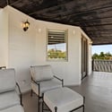 Upper balcony lounge with covered shade, ceiling fan, and peaceful backyard views enhancing indoor-outdoor living.