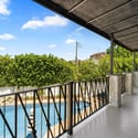 Quiet balcony retreat featuring seating space and open views, perfect for relaxing while overlooking the backyard and pool area.