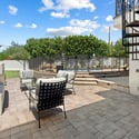Charming patio with built-in fireplace, paver flooring, and intimate seating creating a cozy outdoor gathering space.
