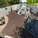 Backyard play zone featuring an in-ground trampoline and play structure, offering a fun and functional outdoor setup.