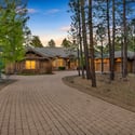 Elegant mountain retreat with a welcoming front entry, mature pine setting, stone detailing, and timeless curb appeal in the prestigious Forest Highlands community.