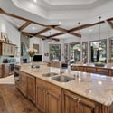 Gourmet kitchen with custom cabinetry, oversized islands, expansive windows, and seamless flow into the great room with beautiful golf course and forest views.