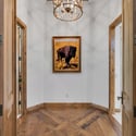 Elegant hallway with statement chandelier, custom wood flooring, and upscale architectural details leading into the luxurious primary suite retreat.