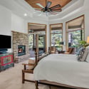 Luxury primary bedroom featuring a cozy stone fireplace, oversized windows, and beautiful golf course surroundings that create a private retreat experience.