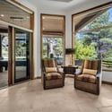 Relaxing bedroom sitting area with panoramic windows, natural light, and tranquil pine tree views that bring the beauty of Flagstaff indoors.
