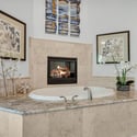 Luxury primary bathroom featuring a relaxing soaking tub, elegant fireplace detail, granite countertops, and spa-inspired finishes perfect for mountain retreat living.