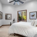 Inviting guest bedroom with large picture windows, soft natural light, high ceilings, and peaceful mountain-inspired design throughout the luxury home.