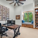 Spacious bedroom with built-in window bench seating, custom shelving, tall ceilings, and beautiful natural light throughout the inviting living space.