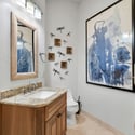 Sophisticated guest bathroom with walk-in glass shower, granite vanity top, custom wood cabinetry, and modern finishes throughout the luxury home.