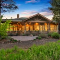 Spectacular rear exterior with expansive covered entertaining areas, custom architectural details, and lush landscaping nestled among towering pine trees.